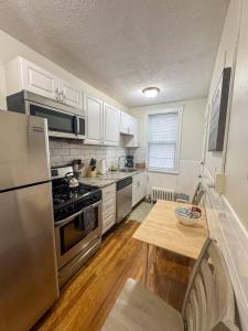 a kitchen with white cabinets and a stainless steel refrigerator at Mile To Longwood Medical, Renovated, Pub Trans in Brookline +5 photos