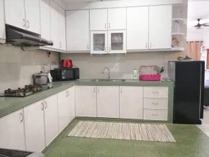 a kitchen with white cabinets and a black refrigerator at Arfaan Guest House in Skudai