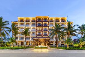 a large building with palm trees in front of it at Wyndham Garden Hoi An Cua Dai Beach in Hoi An