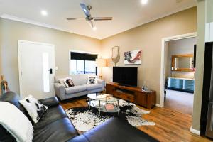 a living room with a couch and a tv at Sterling House Spacious Deck BBQ Pet Friendly in Dubbo