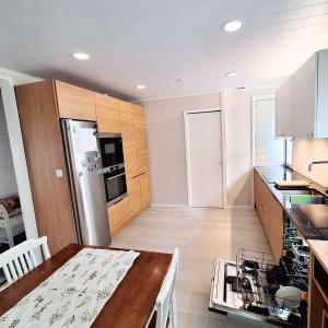 ロヴァニエミにあるVilla Repoの白いキャビネットと木製のテーブルのあるキッチン