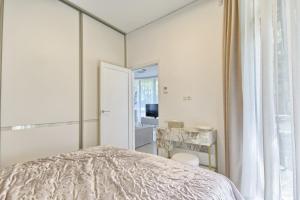 a white bedroom with a bed and a mirror at Home In 2 in Druskininkai