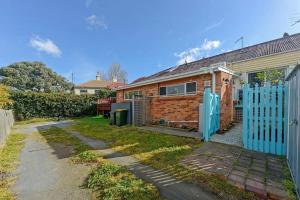 ein Backsteinhaus mit blauem Tor und Auffahrt in der Unterkunft Mr Watson's Cottage near the Battery Point Jetty in Hobart