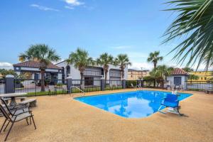 a swimming pool with a table and chairs next to a building at Baymont by Wyndham Mobile/Tillmans Corner in Tillmans Corner