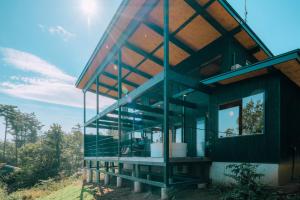 ein Haus mit Glaswänden und einem Dach in der Unterkunft ママを癒す森のサウナ -子連れ歓迎 やさしいサウナと簡単ごはん付き- 一棟貸し -ご家族限定- in Komoro