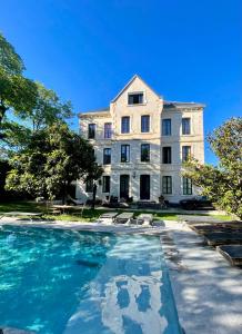 a large white building with a swimming pool in front of it at Demeure Saint Louis Historic manor, City 700m, parking,A C,Clim,WIFI, heated pool, city view in Carcassonne
