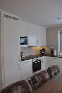 une cuisine avec des armoires blanches et une table et des chaises dans l'établissement Leilighet sentralt på Sjusjøen, 11 sengeplasser, à Ringsaker