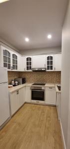 a white kitchen with white appliances and wooden floors at Mina Apartment in Tirana +5 photos