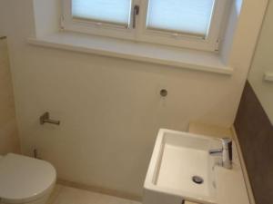 a bathroom with a sink and a toilet and a window at Sylthus-Haithabu in Wenningstedt