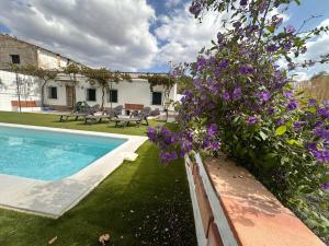 a garden with purple flowers next to a swimming pool at El Cortijo in Archidona