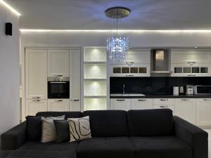 a living room with a black couch in front of a kitchen at TAM Serviced 2BDR Apartment City Center No6 in Tirana