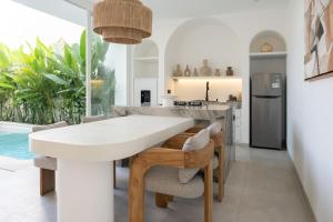 een keuken en eetkamer met een witte tafel en stoelen bij White Palm Villa in Canggu