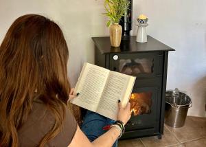 a woman reading a book in front of a fireplace at Las casillas de la Villa: TANGO in Montefrío