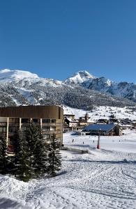 a building in the snow with mountains in the background at Chalmettes Lune Étoilée in Montgenèvre