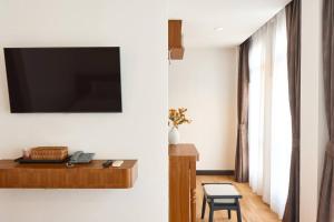 a living room with a tv on a wall at Be Phrasingh Hotel Chiang Mai in Chiang Mai