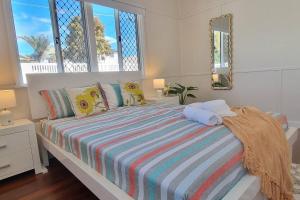 a bedroom with a bed with a striped blanket and windows at The Heavenly Haven in Brisbane