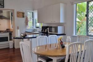 a kitchen with a wooden table and white chairs at The Heavenly Haven in Brisbane