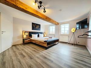 a bedroom with a large bed and a wooden floor at Moritz Apartments - Apartment Pfarrgasse 11 - in Küllstedt