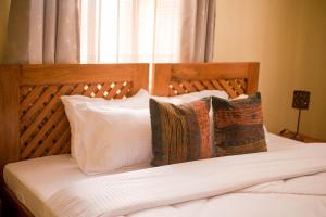a bedroom with a bed with white sheets and pillows at Hecasa Apartments in Arusha +78 photos