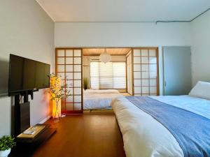 a bedroom with two beds and a flat screen tv at OMOTENASHI STAY OSAKA 41m2 1LDK 十三駅徒歩1分 梅田2分 神戸京都アクセス良好 和室のある家 in Osaka
