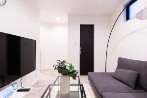 uma sala de estar com um sofá e uma TV em J S暁宅-星白2F hoshishiro2F em Osaka