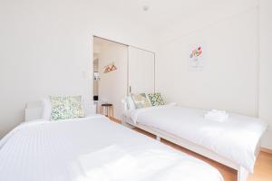 a white bedroom with two beds and a mirror at mori house西が丘 in Tokyo