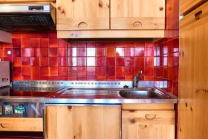 een keuken met een wastafel en een rode betegelde muur bij Villa Antermont in Canazei