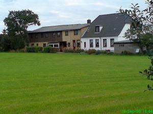 a large house with a large field of green grass at Ferienwohnung Thomsen in Taarstedt