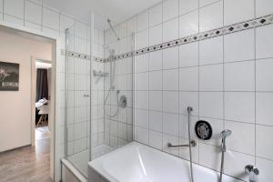 Villa Eichwald Appartements في فرودنستاد: حمام من البلاط الأبيض مع حوض استحمام ودش +41 صورة