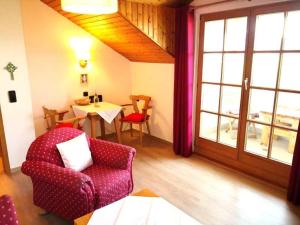 a living room with a red chair and a table at Ferienwohnungen Haus Irene in Bodenmais