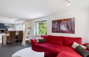 Villa Eichwald Appartements في فرودنستاد: غرفة معيشة مع أريكة حمراء وطاولة
