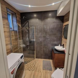 a bathroom with a shower and a washing machine at Stilren svit lägenhet med trädäck och laddstation in Motala +5 photos
