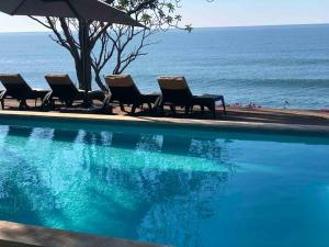 eine Reihe von Stühlen neben einem Pool in der Unterkunft Casa Las Doroteo in El Sunzal