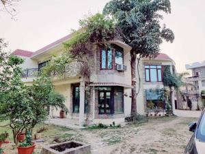 a large house with trees in front of it at Basti House - Boutique Homestay in Lucknow