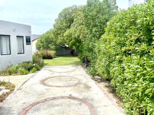 a walkway leading to a yard with trees and a building at Kelp Cottage - Two Private Garden en-suite Rooms in Gansbaai +3 photos
