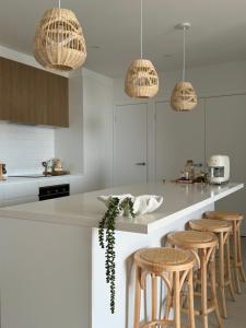 a kitchen with white cabinets and bar stools at Sunshine Coast Paradise in Maroochydore