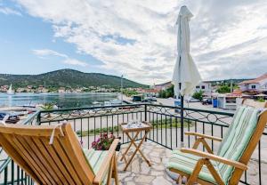 a balcony with two chairs and an umbrella at House Dinko in Vinišće