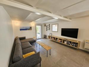 a living room with a couch and a flat screen tv at Elegante maison avec un beau jardin, à 150 m de la mer, climatisation, Wifi ... in Saint-Mandrier-sur-Mer