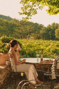 a woman sitting at a table with a glass of wine at La Bastide de Marie, Maisons et Hôtels Sibuet in Ménerbes
