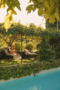 a woman sitting in a chair next to a swimming pool at La Bastide de Marie, Maisons et Hôtels Sibuet in Ménerbes +81 photos