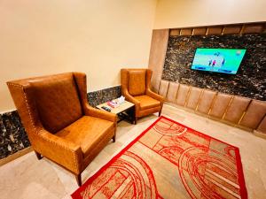 ein Wohnzimmer mit zwei Stühlen und einem Fernseher in der Unterkunft Blue Moon Residency in Islamabad