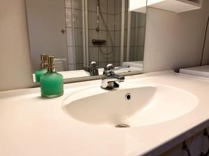 a bathroom sink with a green soap dispenser on it at Hjertet av Stavanger in Stavanger +24 photos