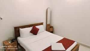 - une chambre avec un lit doté de draps blancs et d'oreillers rouges dans l'établissement Ripples Backwater Resort, Kollam, à Kollam