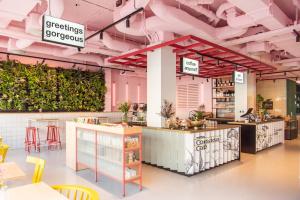 a restaurant with pink ceilings and green plants at Conscious Hotel Vondelpark in Amsterdam