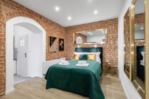 sypialnia z zielonym łóżkiem z ceglaną ścianą w obiekcie Apartamenty KB Toruń w Toruniu