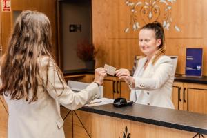 Kobieta podająca kobiecie kartę kredytową w obiekcie Hotel Maria & Spa w mieście Szczawnica