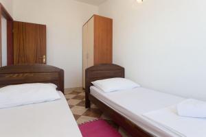 two beds in a small room with white sheets at Apartment Sanda in Stomorska