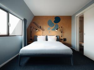 a bedroom with a bed and a wall with lamps at Conscious Hotel The Tire Station in Amsterdam