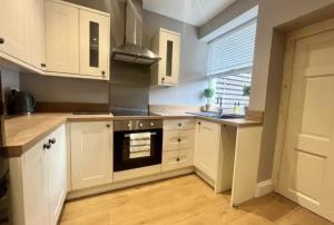 a kitchen with white cabinets and a stove at Queens Cottage in Skipton