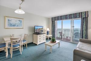 a living room with a couch and a table with a television at Bay Watch Resort | Oceanfront | King Suite | Budget Friendly in Myrtle Beach